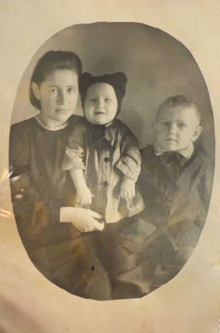 Старая фотография в овальном паспарту: молодая женщина с малышом на руках и мальчик