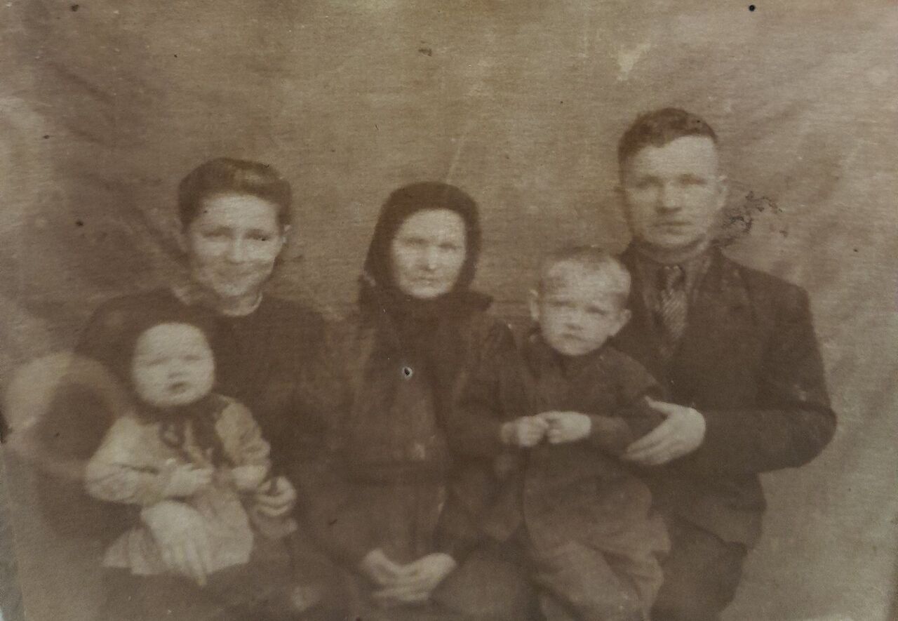 Старая семейная фотография: мужчина, две женщины (одна — в платке) и двое малышей